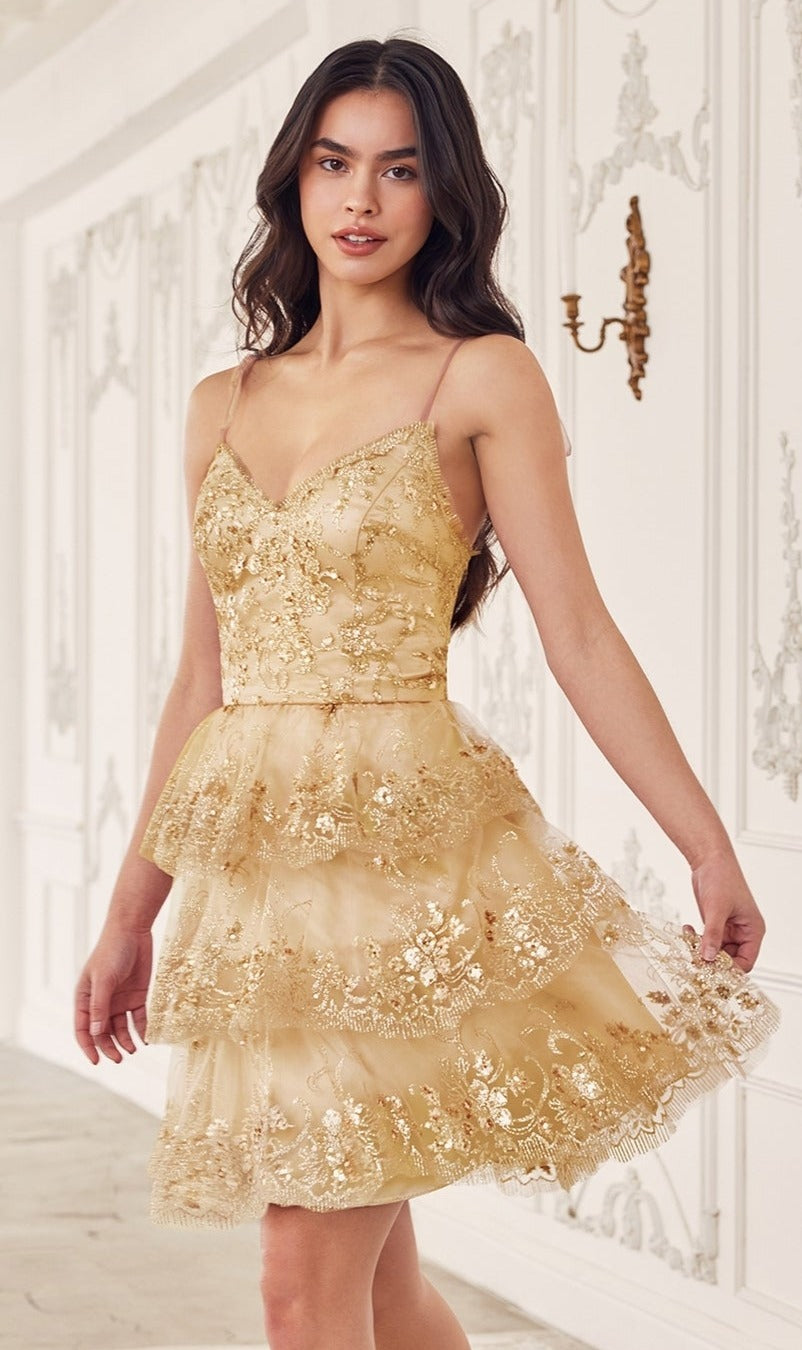 A woman in the Sequin-Print Short Ruffled Homecoming Dress KV1090 stands in an ornate white room with decorative wall panels and a gold sconce.